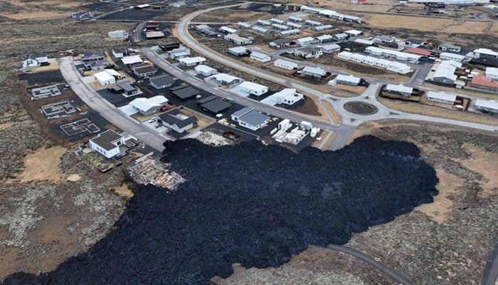 An aerial view taken on January 15, 2024 shows a lava stream near houses in Grindavik, southwest of the capital Reykjavik, after a volcanic eruption. — AFP