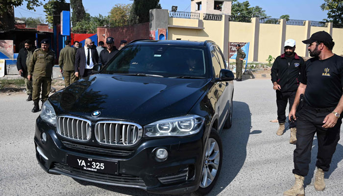 Security personnel guard a vehicle carrying Bushra Bibi, the wife of jailed former Pakistan prime minister Imran Khan, as she leaves Adiala Jail in Rawalpindi on December 2, 2023, after attending a hearing for her husband at a special court. — AFP