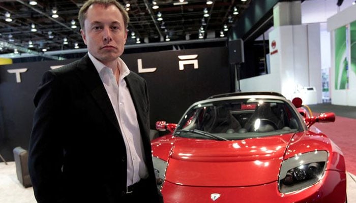 Elon Musk bir Tesla arabasının yanında duruyor.  — Mike Cheslik/Dosya