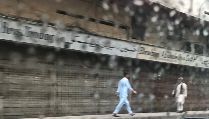 People walk on a street in Karachi amid rainfall. — Geo.tv