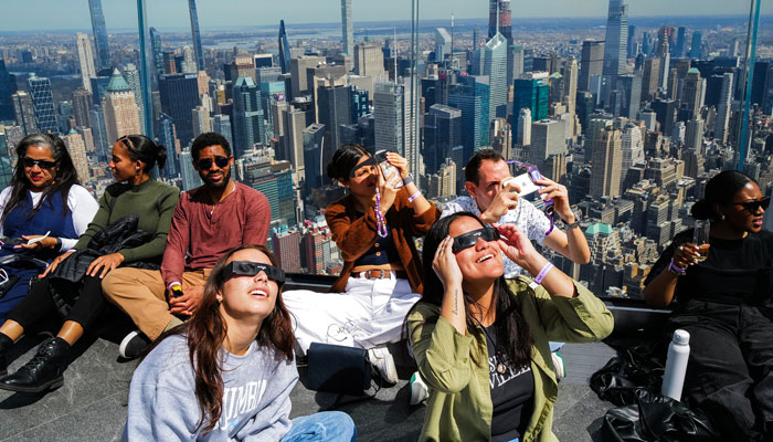 People look toward the sky at the Edge at Hudson Yards observation deck in New York, on April 8, 2024. — AFP