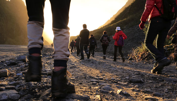 Representational image of people walking on a mountainous road. — Unsplash