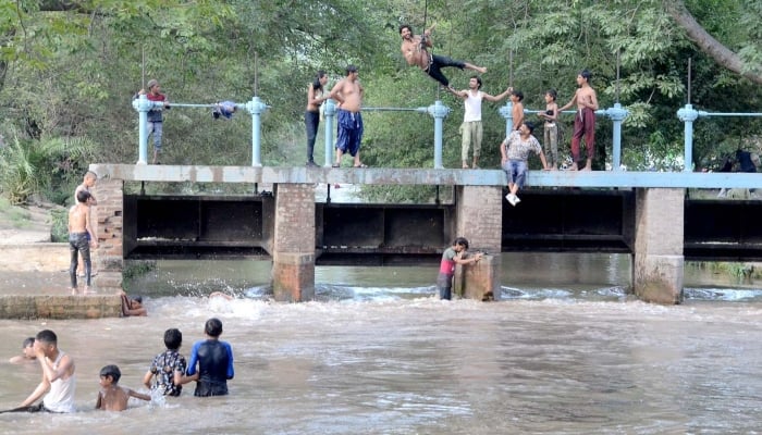 Youngsters are jumping into the canal to alleviate the sweltering heat in Lahore on September 8, 2023. —APP