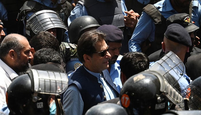 Police escort former Imran Khan (C) as he arrives at the high court in Islamabad on May 12, 2023. — AFP