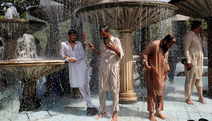 Men cool off in a fountain in Karachi. — Reuters/File