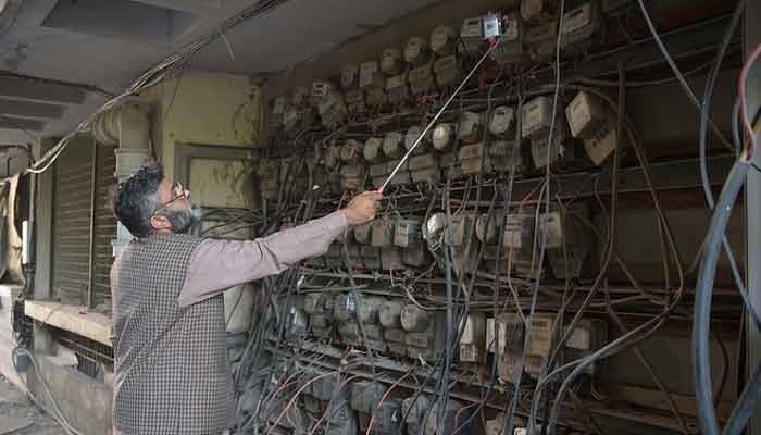 An employee of the Islamabad Electric Supply Company (IESCO) takes a meter reading with his smartphone at a commercial building in Islamabad. — AFP/File