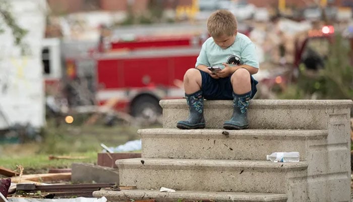 Tornado batters down Iowa, leaving destruction in its trails. (Hudson Vanatta, 6, is seated on the steps of a home that has been destroyed in Greenfield, while his father assists with firefighting duties. — Chris Juhn)
