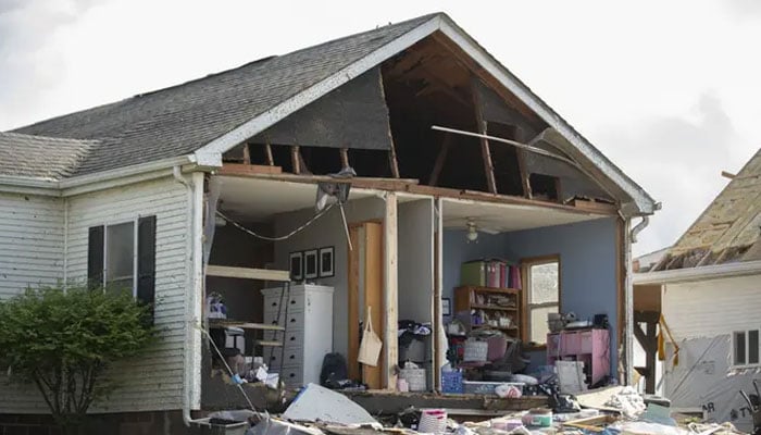 A house in Greenfield sustained severe damage, with its front completely destroyed, yet remarkably, the interior remained intact with pictures still hanging on the walls. — Chris Juhn