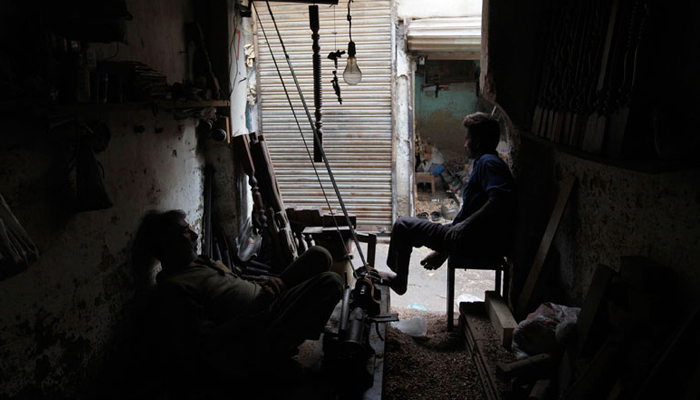 Carpenters at a workshop pause during a power outage in Karachi, on June 15, 2013. — Reuters