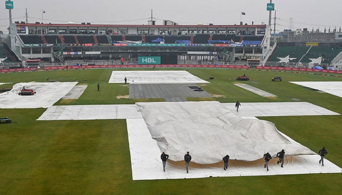 Ground staff covers the pitch as it rains and delays the start of the Pakistan Super League (PSL) T20 cricket match between Peshawar Zalmi and Lahore Qalandars in the Rawalpindi Cricket stadium in Rawalpindi on March 2, 2024. — AFP