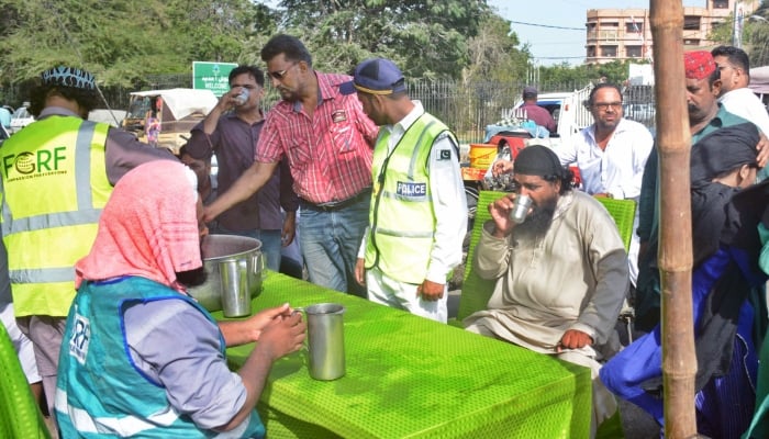 Volunteers giving water to people at a heatwave camp established in Karachi as the city experiences hot and humid weather on May 21, 2024. —APP