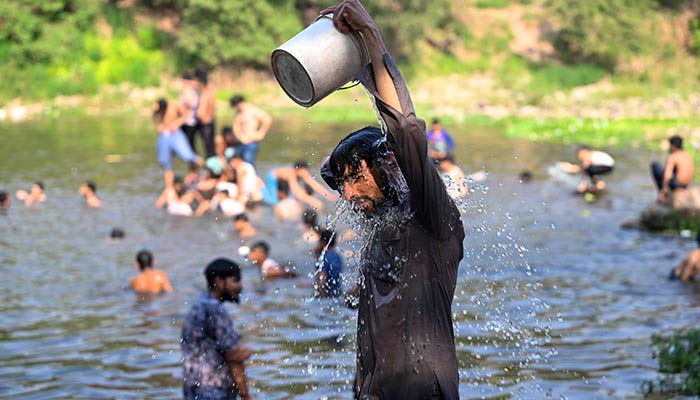 Boys bathe in the waters of Rawal dam on a hot summer day in Islamabad on May 23, 2024. — AFP