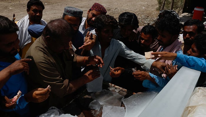 People buy ice blocks from a vendor during a hot summer day, as the heatwave continues in Jacobabad, May 26, 2024. — Reuters
