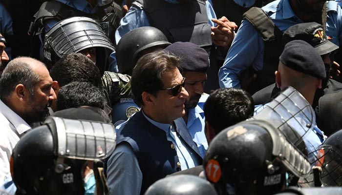 Police escort former Imran Khan (centre) as he arrives at the high court in Islamabad on May 12, 2023. — AFP