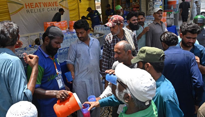 Volunteers distribute water and cold drinks to bypassers at a ´heatwave relief camp´ along the street during a hot summer day in Karachi on May 22, 2024. — AFP