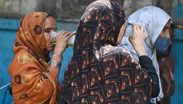 Women drink sugarcane juice at a roadside stall on a hot summer day in Karachi on May 30, 2024, amid the ongoing heatwave. — AFP