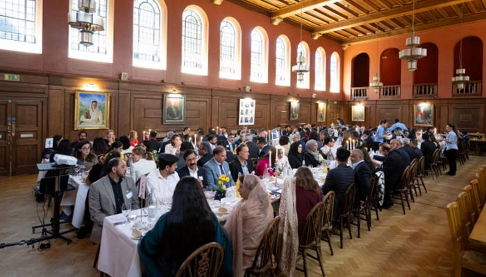 Attendees of the event seen sitting on a dining table. — Oxford Pakistan Programme