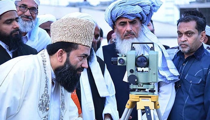 Central Ruet-e-Hilal Committee Chairman Maulana Abdul Khabeer Azad looks through a telescope for sighting of the new moon in Peshawar.—APP/File