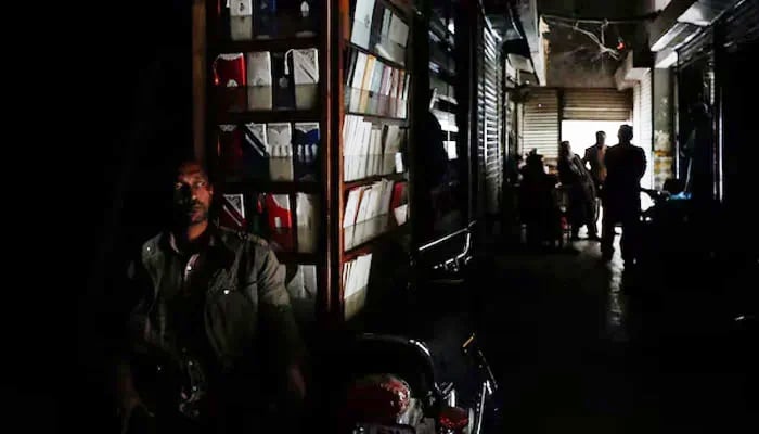 A man sits outside his shop during a power breakdown in Pakistan. — Reuters/File