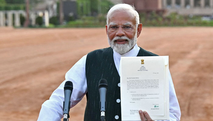 Indian PM Narendra Modi shows a letter by President Droupadi Murmu (not pictured) inviting him to form the countrys new government at the presidential palace Rashtrapati Bhavan in New Delhi on June 7, 2024. — AFP
