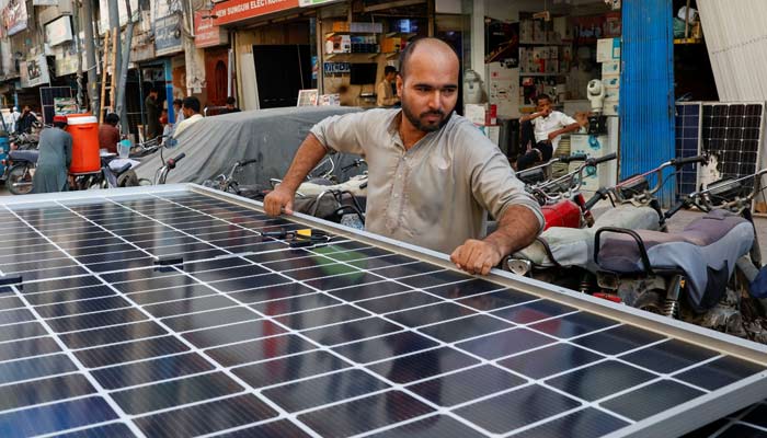 A worker loads solar panels on a vehicle, outside a shop at a market selling electronic items in Karachi, Pakistan June 11, 2024. — Reuters