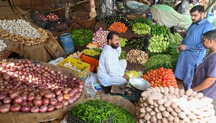 پاکستان میں بڑے پیمانے پر سیلاب کے نتیجے میں اشیائے خوردونوش کی قیمتوں میں بڑے اضافے کے درمیان 29 اگست 2022 کو لاہور کی ایک مقامی مارکیٹ میں سبزیاں خریدنے والے لوگوں کی نمائندہ تصویر۔  — اے ایف پی/فائل