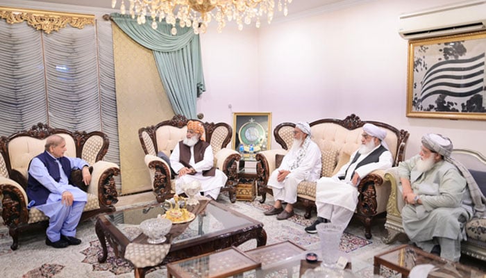 Prime Minister Shehbaz Sharif (left) is seated with JUI-F chief Maulana Fazlur Rehman and his parties senior leaders at his residence in Islamabad on June 13, 2024. — PMO