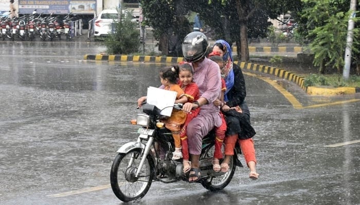 A family rides on a motorcycle during heavy rainfall in Lahore. — Online/File