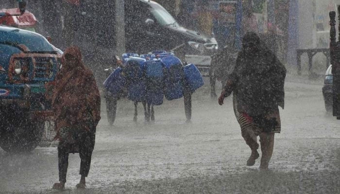 Women walk amid heavy rainfal on a street in Pakistan. — AFP/File
