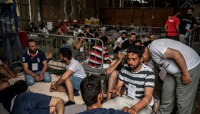 Migrants who were rescued at open sea off Greece along with other migrants, after their boat capsized, sit inside a warehouse, used as shelter, at the port of Kalamata, Greece on June 15, 2023. — Reuters