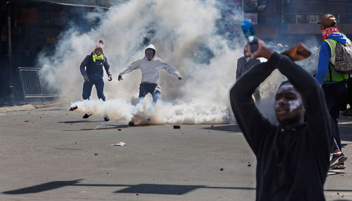 Protesters react to teargas canisters launched at them by riot police during a nationwide strike to protest against tax hikes and the Finance Bill 2024 in downtown Nairobi, on June 25, 2024. — AFP