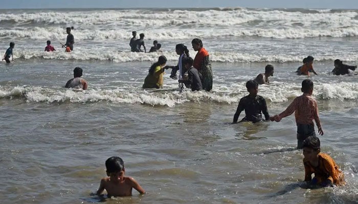 People swim at a Karachi beach. — AFP/File
