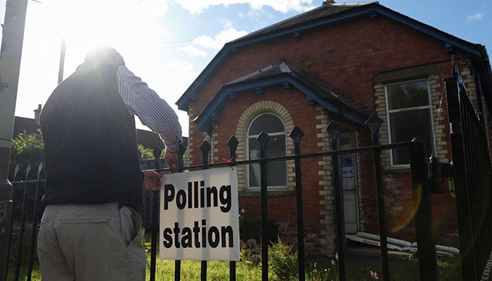 The presiding officer fixes the polling station sign outside a polling station during the general election in Burrelton, Scotland, Britain, July 4, 2024. — Reuters