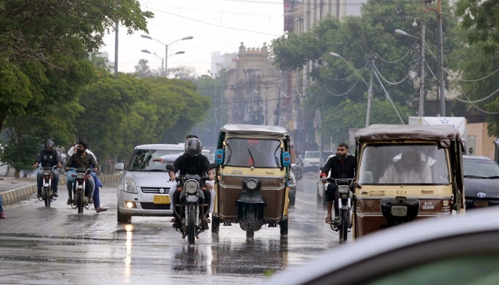 Commuters pass through a road during heavy downpour of monsoon season, at Governor House road in Karachi on July 9, 2024. — PPI