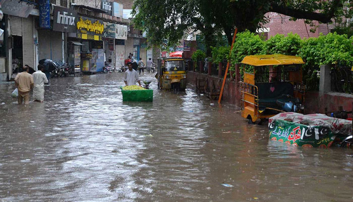 People wading through stagnant rainwater after a heavy downpour in Chiniot on July 6, 2024. — APP