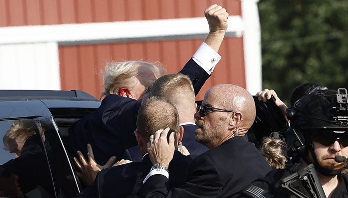 Republican presidential candidate former President Donald Trump pumps his fist as he is rushed into a car at a rally on July 13, 2024 in Butler, Pennsylvania. — AFP