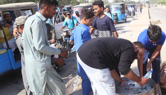 A man distributing cold water bottles during hot weather in Karachi on May 10, 2024. —INP