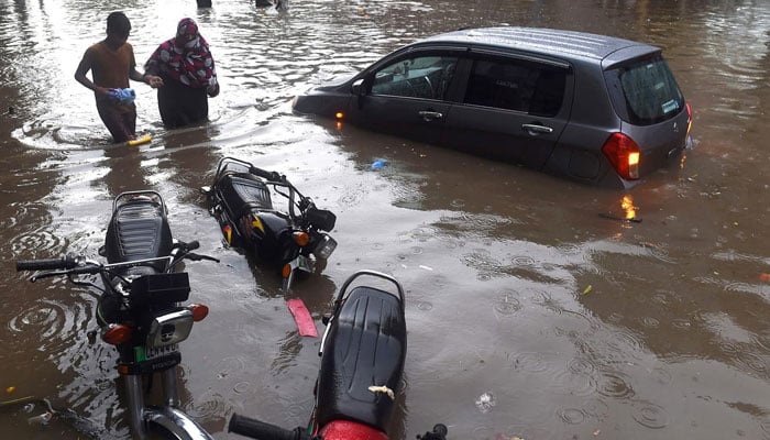 Residents wade along a flooded street after heavy monsoon rains in Lahore. — Reuters/File