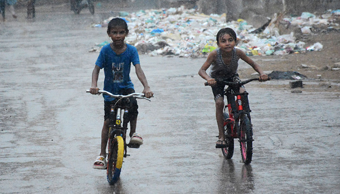 Children enjoy riding bicycles on a rainy day in Karachi on July 20, 2024. — APP