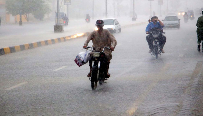 Commuters are passing through a road after downpour of monsoon season, at Nazimabad area in Karachi on July 20, 2024. — PPI