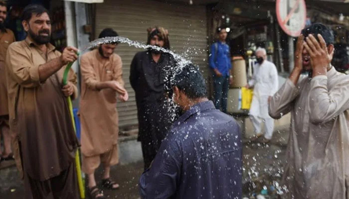 People spray each other with water as extreme heat grips Karachi. — AFP/File