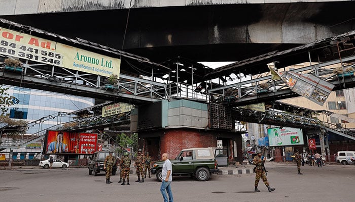 Army soldiers stand guard under a footbridge that was set on fire by a mob during clashes after violence erupted following protests by students against government job quotas, in Dhaka, Bangladesh, July 22, 2024. — Reuters