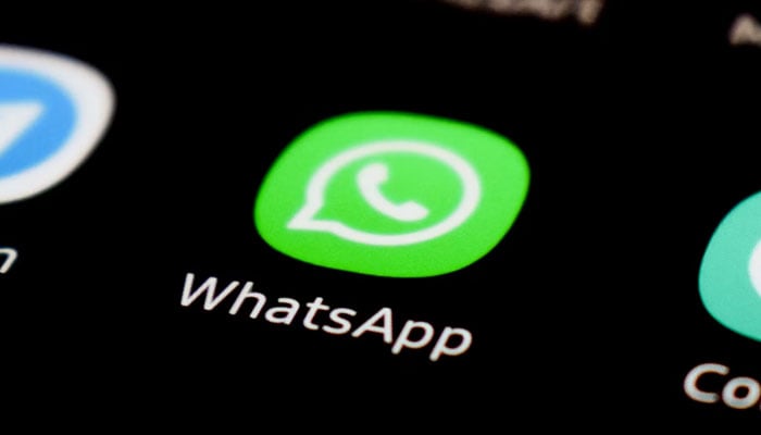 This image shows the WhatsApp app icon displayed on a phone screen. — Unsplash