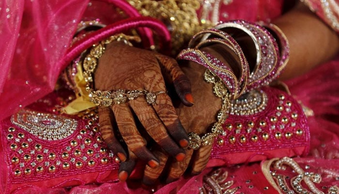 A representational image of bride sitting with her hands crossed in her lap — Reuters