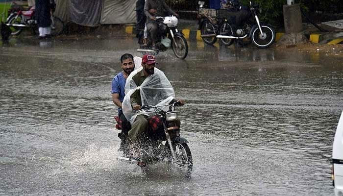 Motorcyclists are passing through a flooded road in Karachi amid heavy rain on September 12, 2022.— APP