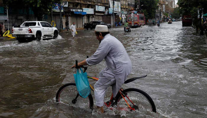 A man rides bicycle along a flooded road, following heavy rains during the monsoon season in Karachi, Pakistan July 25, 2022. — Reuters