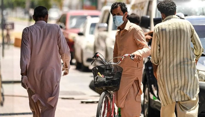 A foreign worker walks pushing a bicycle along a street in the Satwa district of Dubai on May 6, 2020. — AFP