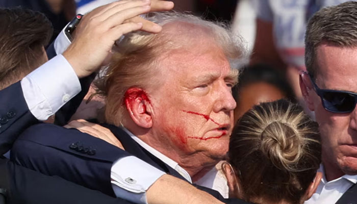 Former US president and Republican candidate for US presidential election 2024 Donald Trump surrounded by the Secret Service after a bullet grazed his ear in an assassination attempt during a campaign rally in Butler, Pennsylvania, US on July 13, 2024. — Reuters