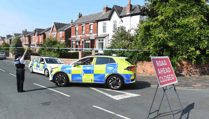 Police officers stand on duty behind a cordon in Southport, northwest England, on July 31, 2024 following clashes after a deadly knife attack. — AFP