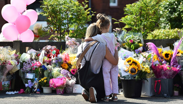 A mother hugs her child as they look at floral tributes for the victims of a deadly knife attack in Southport, northwest England, on July 31, 2024. — AFP